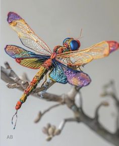 a colorful dragon figurine sitting on top of a tree branch with no leaves