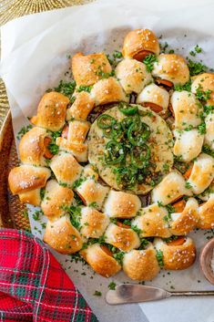 a platter filled with rolls covered in cheese and herbs next to a bowl of dipping sauce