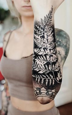 a woman is holding up her arm with tattoos on it