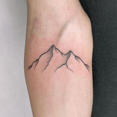 a small mountain tattoo on the arm