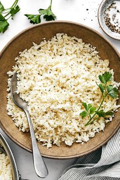 a bowl filled with rice and garnished with parsley next to other dishes