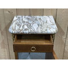 a marble topped end table with drawers