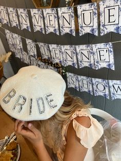 a woman sitting in a chair wearing a white hat with the word bride spelled on it