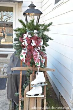 a wooden sled with a christmas wreath and ice skates on it in front of a house