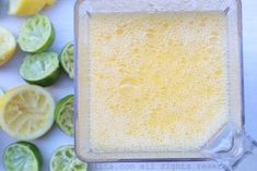 a blender filled with liquid next to sliced limes