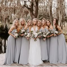 a group of women standing next to each other on a wooden platform in front of trees