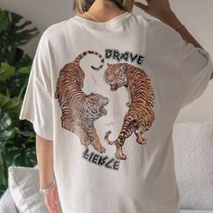 "Tiger Graphic Tee Yin Yang Shirt Good Energy Shirt Fearless Shirt Year Of The Tiger T Shirt Trendy Shirts For Women Y2k Shirt Tiger Shirt ➭ How to Order 1. Choose your shirt size & color options. 2. Select the quantity. 3. Click \"Add to Cart.\" 4. Listen for a knock at your door! ➭ Care Instructions Wash your shirt inside-out in cold water. Do not bleach, dry clean, or iron directly on the design. Tumble dry on low. ➭ Production & Shipping Processing typically takes 1-3 days. Depending on wher Casual White Shirt With Front And Back Print, Casual White Shirt With Print, Trendy Tops With Front And Back Print, Casual Oversized Tops With Front And Back Print, Cotton Relaxed Fit Shirt With Front And Back Print, Cotton Shirt With Front And Back Print, Relaxed Fit, Trendy Short Sleeve Top With Front And Back Print, Relaxed Fit Short Sleeve Shirt With Front Print, Relaxed Fit Shirt With Front Print And Short Sleeves