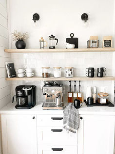 a kitchen with white cabinets and shelves filled with coffee pots, tea kettles and other items