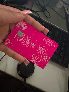 a person holding a pink card in front of a laptop computer with the word fund on it