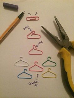 scissors and paper clips are arranged in the shape of a clothes hanger with words written on them