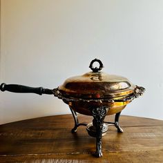 an old fashioned metal pot sitting on top of a wooden table