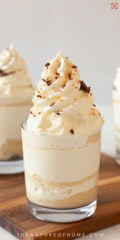 two small desserts with whipped cream and chocolate shaving on top, sitting on a cutting board