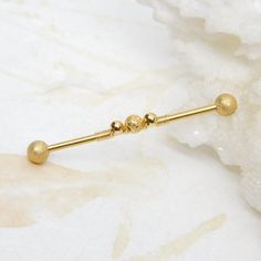 a gold bar with three balls attached to it on a marble surface next to some crystals