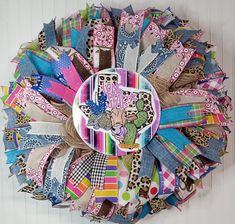 a multicolored wreath made out of fabric and paper with an animal on it