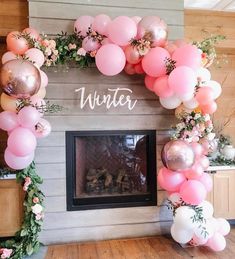 a fireplace decorated with balloons and greenery for an winter party or birthday celebration in front of the fire place