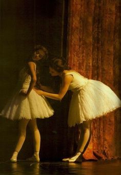 two ballerinas in white tutu skirts are touching each other's hands