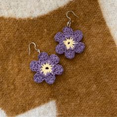 purple crochet flower earrings with white centers on a brown and tan background, ready to wear