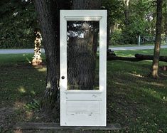 a white door sitting in the grass next to a tree