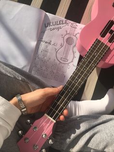 a person holding a pink ukulele in their hands