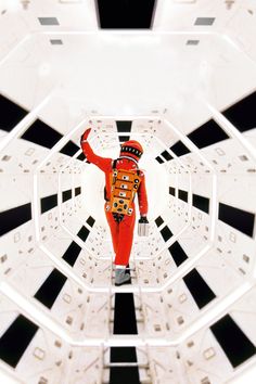 a man in an orange space suit is seen through the center of a white and black structure