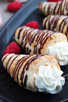 some desserts are on a black plate with raspberries