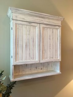 an old white cabinet is hanging on the wall