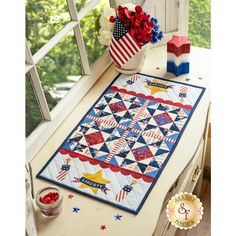 an american flag quilt on a window sill with flowers in the vase next to it