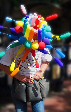 a woman is walking down the street with a bunch of balloons on her head,