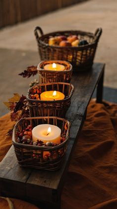 three baskets filled with candles sitting on top of a wooden table