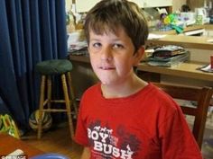 a young boy standing in front of a desk