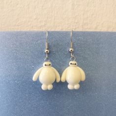 a pair of white earrings with a small dog on the front and back of it