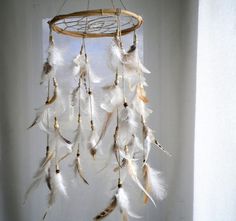 a white dream catcher with feathers hanging from it's side in front of a window