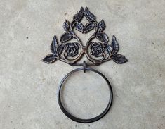 a metal ring with roses on it sitting on the ground next to a wall mounted hook