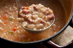 a ladle full of soup with meat and vegetables