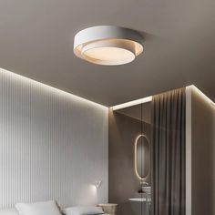 a bed sitting under a round light next to a mirror on the side of a wall