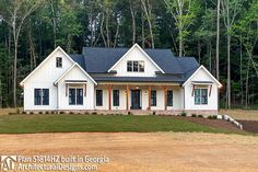 a large white house with black shutters in the front yard and trees behind it