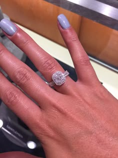 a woman's hand with a diamond ring on her finger and the other hand holding an engagement ring