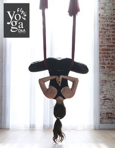 a woman doing aerial acrobatic exercises in front of a window