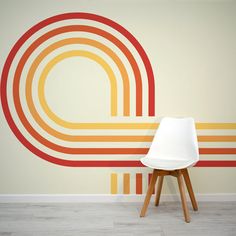 a white chair sitting in front of a wall with an orange and yellow design on it