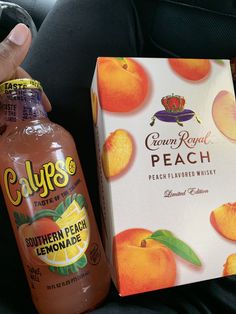 a person holding a bottle of orange juice next to a box of peach lemonade