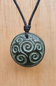 a black and white pendant on a wooden surface with a cord attached to the bead