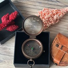 a compass and other items are on a table next to a box with flowers in it