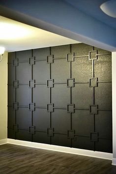 an empty room with wood flooring and black wallpaper on the walls, in front of a light fixture