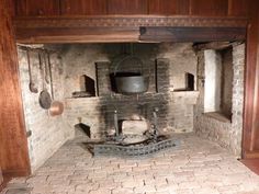 an old fashioned brick oven with pots and pans on the stove top in a wood paneled room