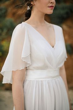 a woman wearing a white dress standing outside