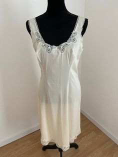 This is a beautifully feminine French below knee lingerie Slip. Made by HELIOS, Paris. 1950's Quality French lingerie. Fabric - Nylon. Shimmering oyster white satin fabric with floral lace trim around the neckline and hem. No size label. I would estimate a 'Large'. Measurements laid flat: Below the Bust 43cm Hips 56cm Length 96cm (from top of shoulder strap to hem) 'New Old Stock' Unworn - fabulous condition. No tags. Beige Fitted Sleepwear With Lace Trim, Fitted Beige Sleepwear With Lace Trim, Fitted Sheer Cream Nightgown, Fitted Sleeveless Chemise For Wedding, Coquette Daywear Fitted Chemise, Fitted Coquette Daywear Chemise, Feminine Fitted Cream Nightgown, Fitted Coquette Chemise For Daywear, Fitted Cream Nightgown In Feminine Style