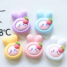 four different colored plastic buttons with ears and nose designs on them, sitting next to each other