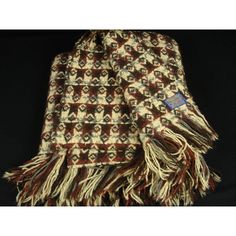 a brown and white scarf with fringes on top of black background in front of a black backdrop