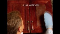 a man standing in front of a wooden cabinet with the words just wipe on it