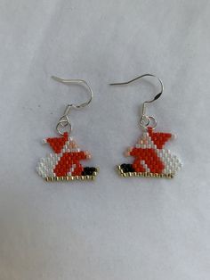 a pair of red and white beaded earrings with santa riding a sleigh